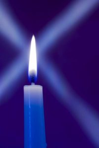 Burning candle with star burst on blue background