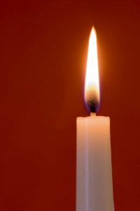 Burning candle on red background